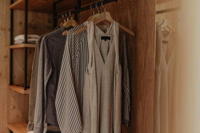 Kleidung auf Holzbügeln in der offenen Garderobe vor der Holzwand