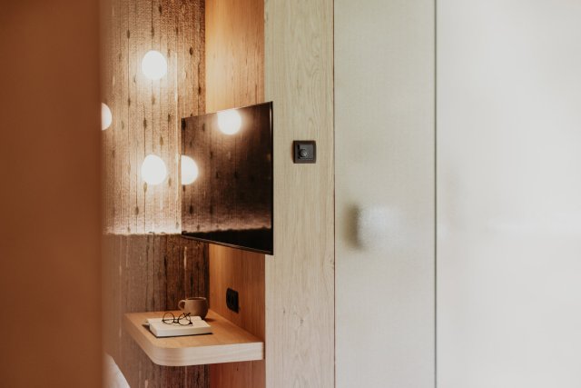 Schwenkbarer Fernseher an der gewebten Wand über einer schwebenden Ablage mit Buch und Tasse